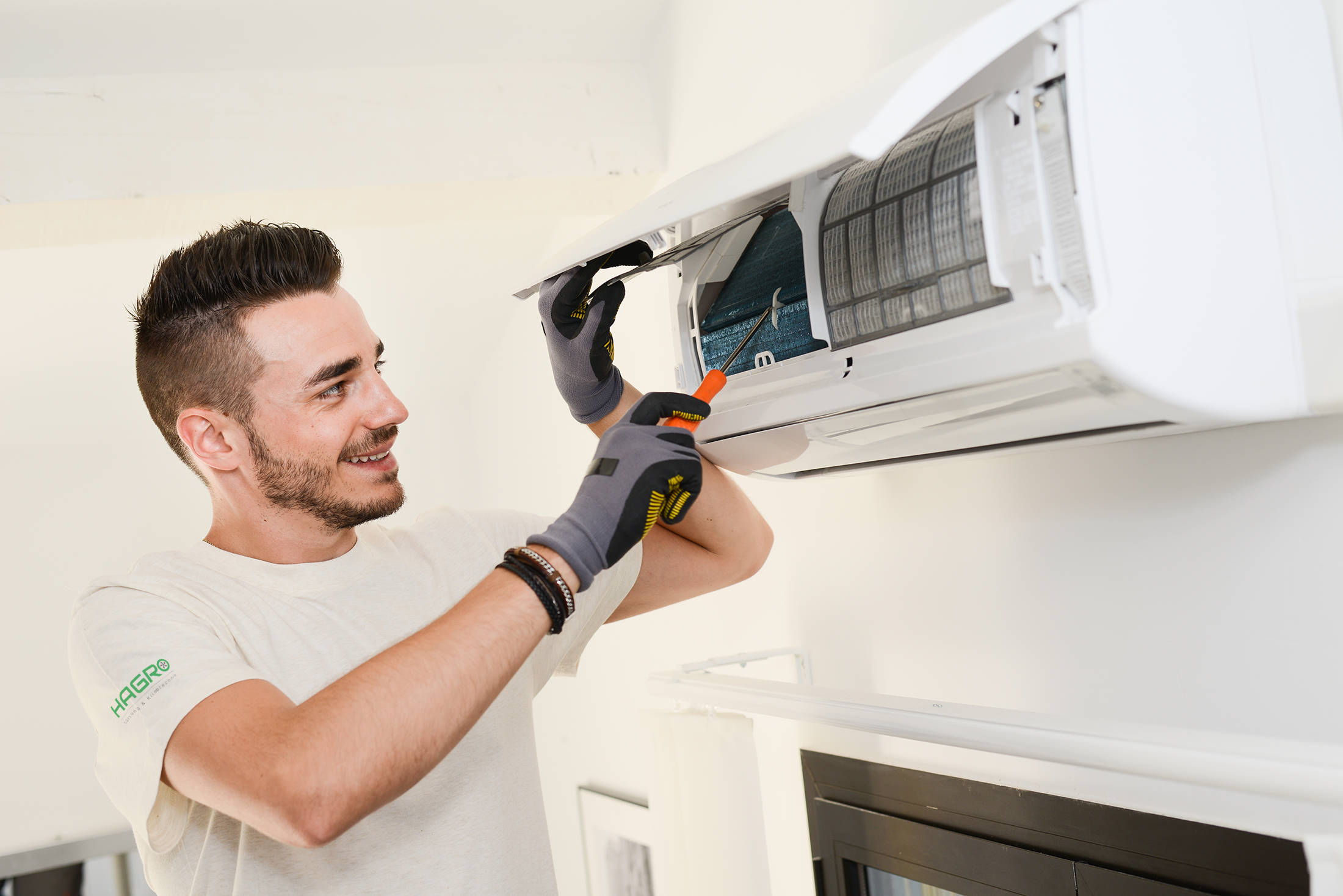 handsome young man electrician installing air conditioning in client house handsome young man electrician installing air conditioning in client house